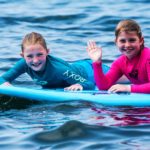 two girls laying on a surfboard