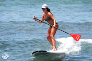 Stand up paddle boarder riding a wave in Kona, Hawaii.