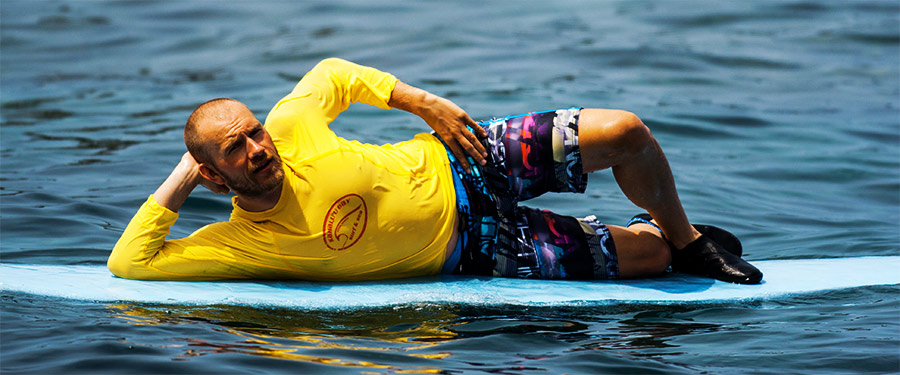 Surfer Posing on a Surfboard wearing SPF Rashguard, Boardshorts and Reef Shoes