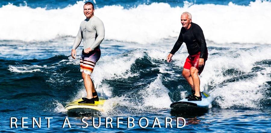 surfers riding wave on rental surfboards in Kona, Hawaii